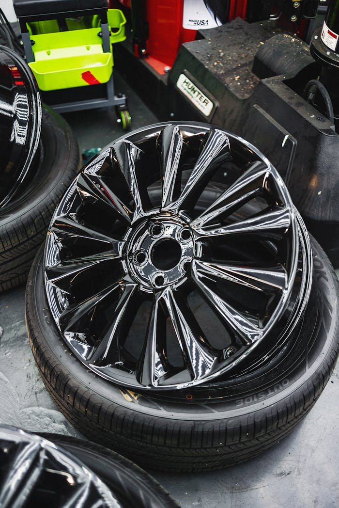 About Glossy black car wheel rim and tire stack in an automotive workshop.